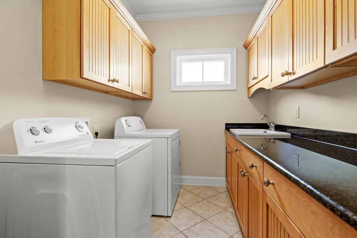 A bright, efficient laundry area featuring a modern washer and dryer, a practical countertop for folding clothes, and overhead cabinets for organized storage. The space is tidy and designed for convenience, reflecting the comfort of in-home amenities.